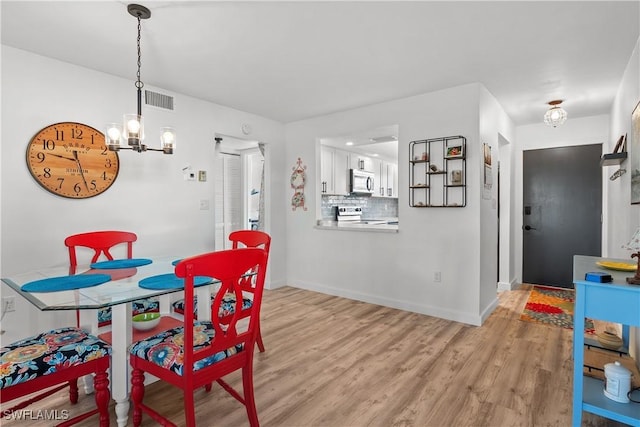 dining area with light wood-type flooring and a notable chandelier