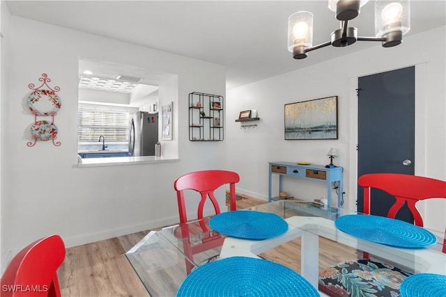 dining room featuring a notable chandelier, light wood-type flooring, and sink