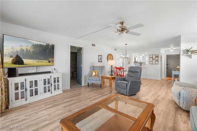 living room with ceiling fan with notable chandelier and light hardwood / wood-style flooring