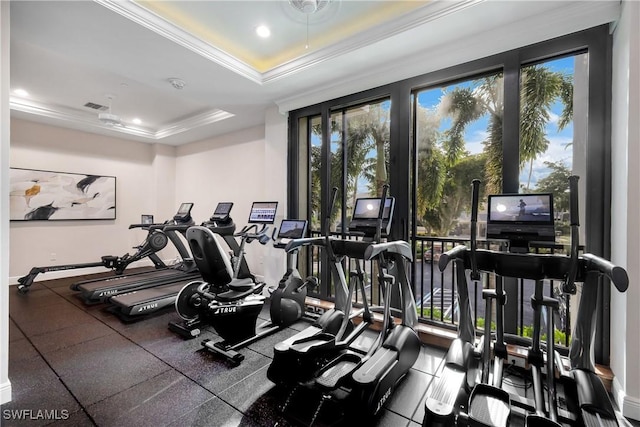 exercise room with a raised ceiling and ornamental molding