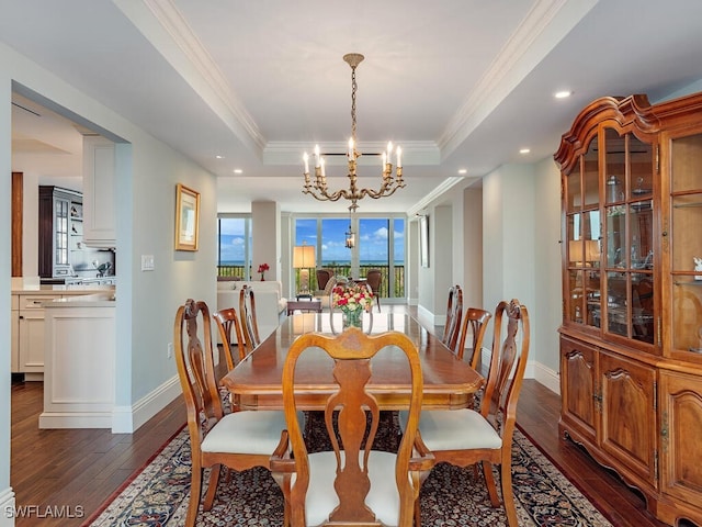 dining room featuring a chandelier, dark hardwood / wood-style flooring, a tray ceiling, and ornamental molding