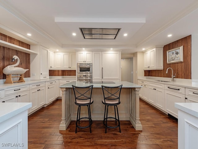 kitchen featuring a kitchen breakfast bar, white cabinetry, sink, and a kitchen island