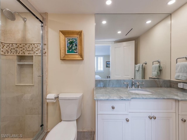 bathroom with vanity, toilet, and a shower with door