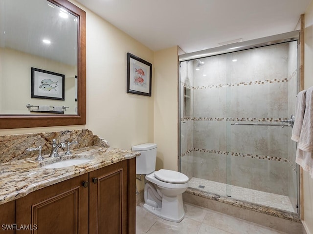 bathroom with tile patterned flooring, vanity, toilet, and a shower with shower door