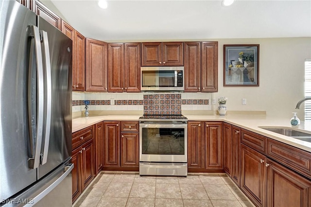 kitchen featuring sink, light tile patterned floors, backsplash, and appliances with stainless steel finishes