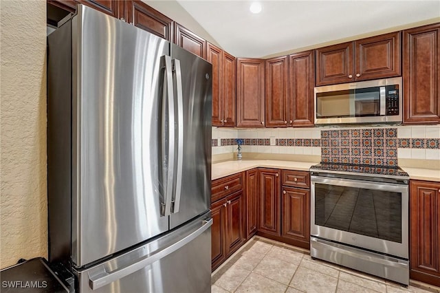 kitchen with tasteful backsplash, light tile patterned floors, stainless steel appliances, and lofted ceiling