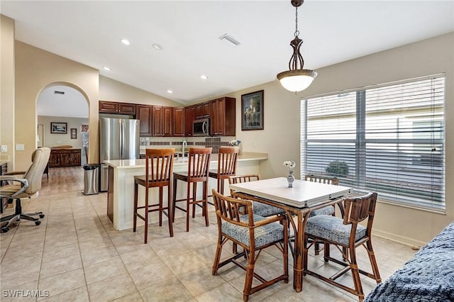 tiled dining room with lofted ceiling and sink