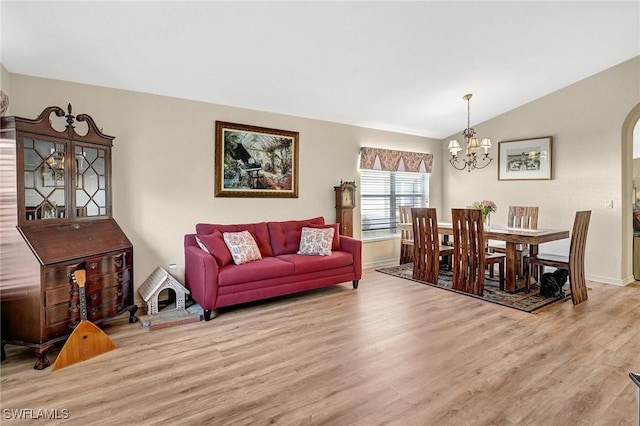 living room featuring vaulted ceiling, light hardwood / wood-style flooring, and a notable chandelier