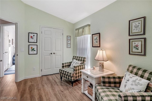 sitting room with vaulted ceiling, plenty of natural light, and light hardwood / wood-style floors