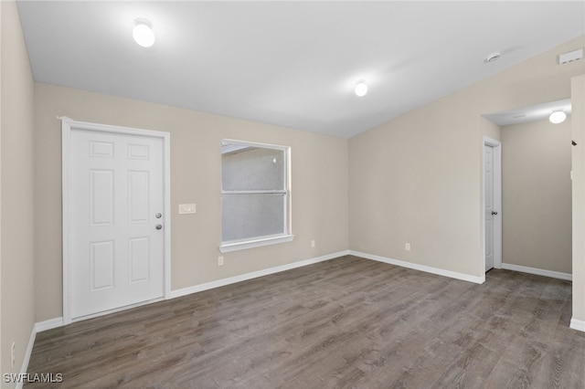 empty room with hardwood / wood-style floors and lofted ceiling