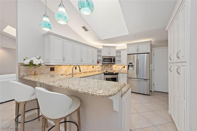 kitchen featuring stainless steel appliances, a kitchen breakfast bar, kitchen peninsula, pendant lighting, and vaulted ceiling