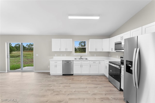 kitchen with white cabinets, appliances with stainless steel finishes, light hardwood / wood-style flooring, and lofted ceiling