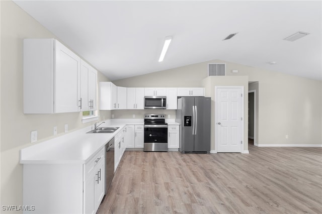 kitchen with light wood-type flooring, stainless steel appliances, vaulted ceiling, sink, and white cabinetry