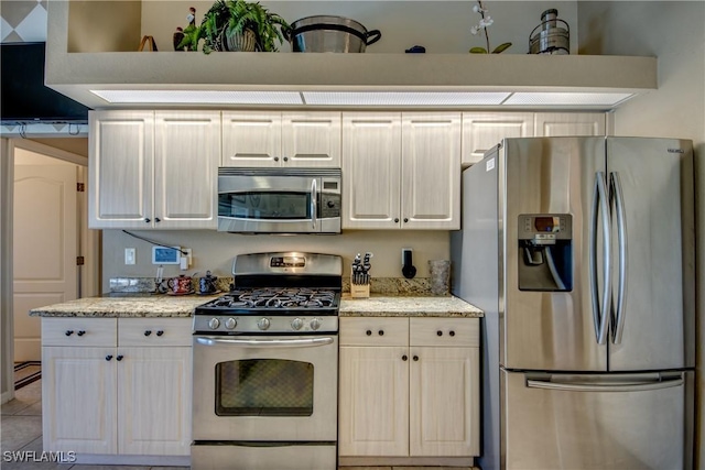 kitchen featuring light stone countertops, light tile patterned floors, and stainless steel appliances