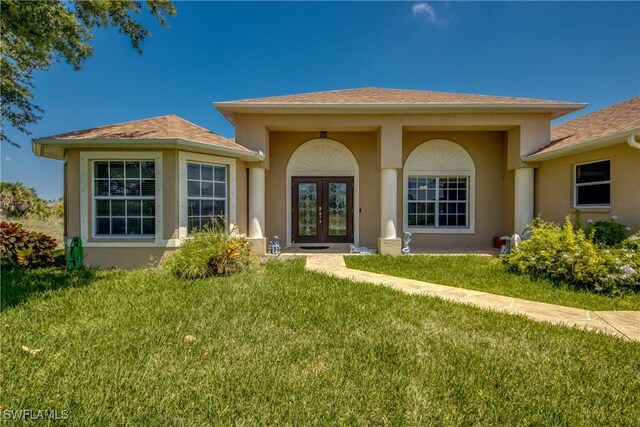 doorway to property with a lawn and french doors