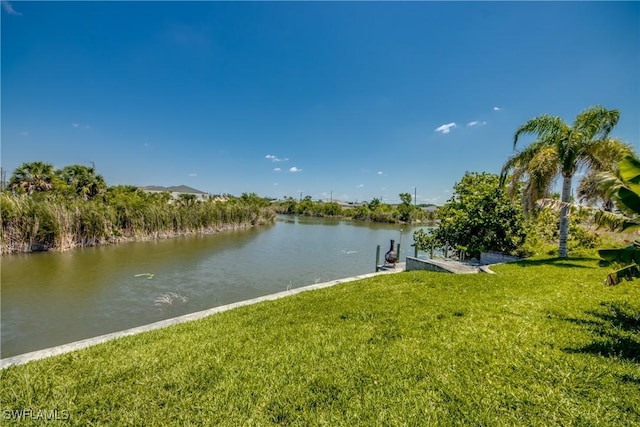 view of dock with a yard and a water view