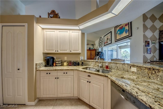 kitchen featuring dishwasher, light stone counters, light tile patterned floors, and sink