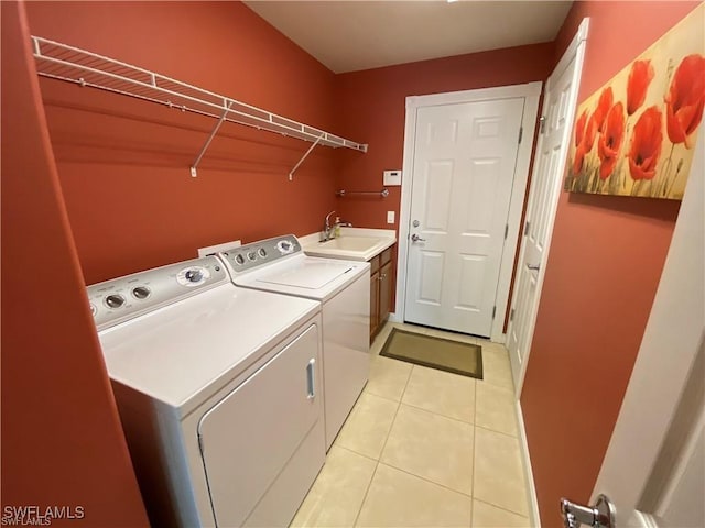 laundry area featuring cabinets, light tile patterned floors, washing machine and clothes dryer, and sink