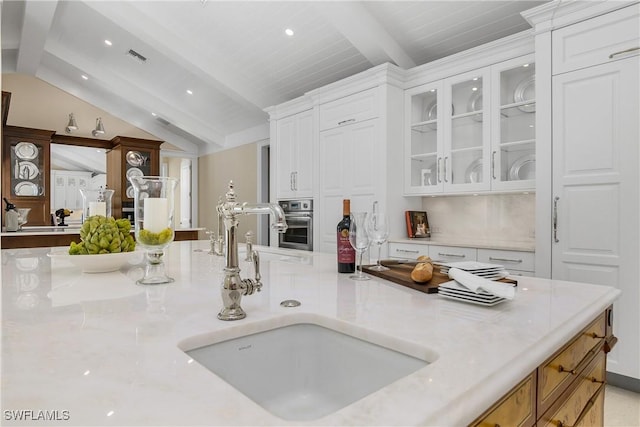 kitchen featuring oven, lofted ceiling with beams, sink, white cabinetry, and wood ceiling