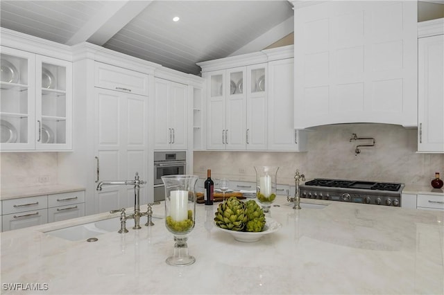 kitchen featuring decorative backsplash, light stone counters, white cabinetry, and sink