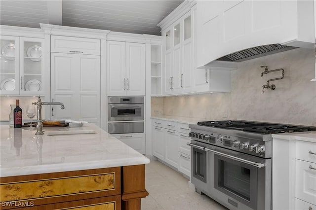 kitchen featuring white cabinetry, sink, premium range hood, and stainless steel appliances