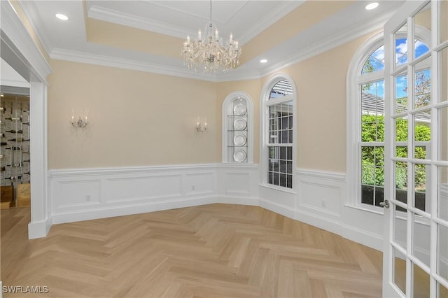 unfurnished dining area with light parquet flooring, a tray ceiling, and ornamental molding