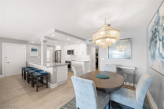 dining room with a notable chandelier and light wood-type flooring