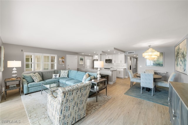 living room with light hardwood / wood-style flooring and an inviting chandelier