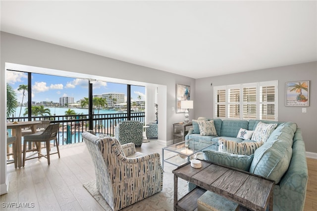 living room featuring light wood-type flooring, plenty of natural light, and a water view