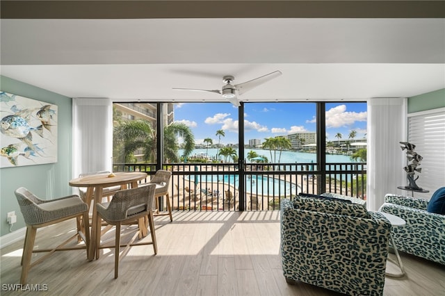 sunroom featuring ceiling fan and a water view