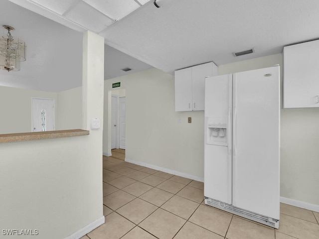 kitchen with white cabinets, white fridge with ice dispenser, and light tile patterned floors