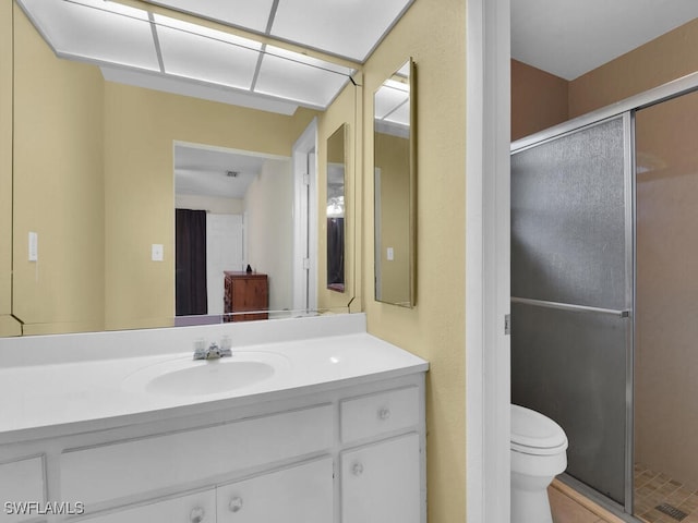 bathroom featuring a shower with door, toilet, and vanity