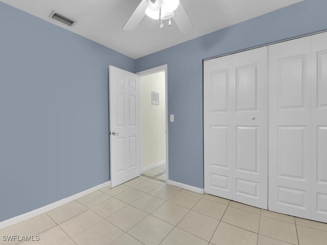 unfurnished bedroom featuring ceiling fan, light tile patterned floors, and a closet