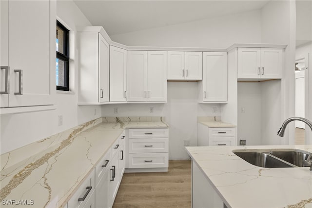 kitchen featuring light stone counters, sink, and white cabinetry