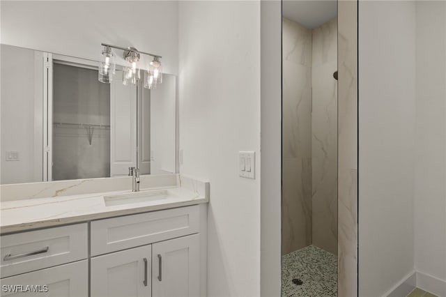 bathroom with a tile shower and vanity