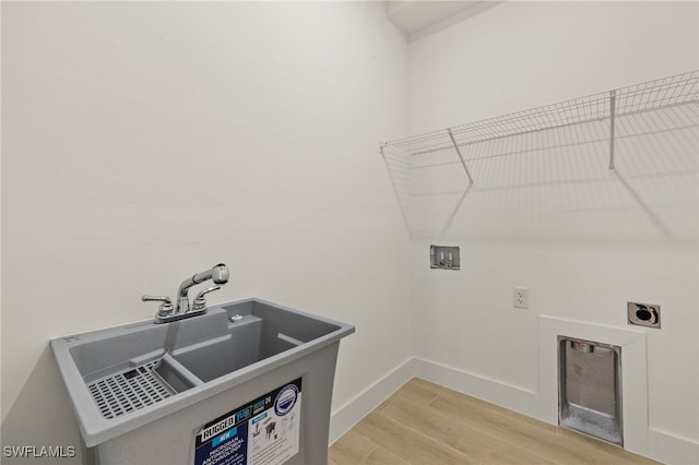 clothes washing area featuring washer hookup, sink, electric dryer hookup, and light wood-type flooring