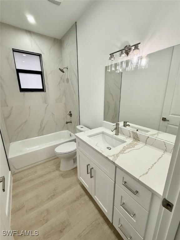 full bathroom with toilet, tiled shower / bath combo, wood-type flooring, and vanity