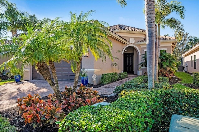 mediterranean / spanish home with central AC unit and a garage