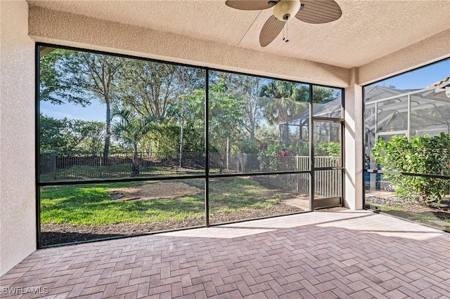 unfurnished sunroom with ceiling fan