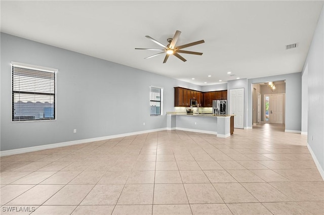 unfurnished living room with light tile patterned floors, a wealth of natural light, and ceiling fan