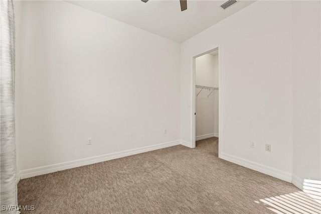 unfurnished bedroom featuring ceiling fan, a closet, light colored carpet, and a spacious closet