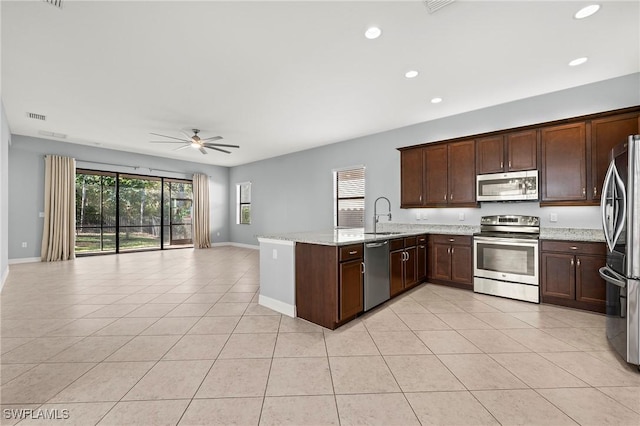 kitchen featuring appliances with stainless steel finishes, light stone counters, ceiling fan, sink, and light tile patterned floors