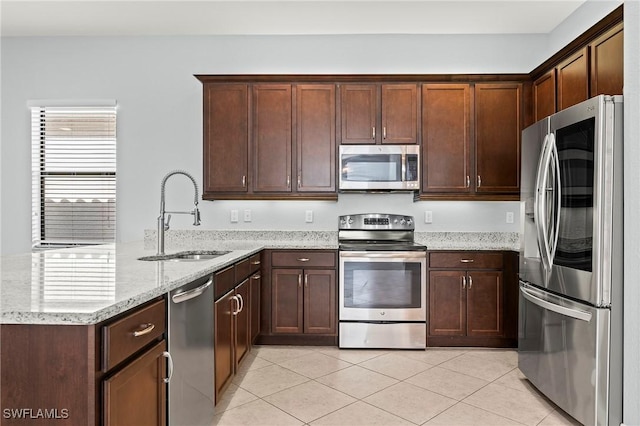 kitchen featuring sink, light tile patterned floors, appliances with stainless steel finishes, light stone counters, and kitchen peninsula