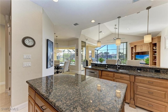 kitchen featuring ceiling fan, sink, a center island, dark stone counters, and decorative light fixtures