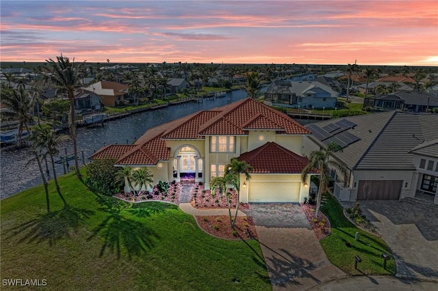 view of front of property featuring a lawn, a garage, and a water view