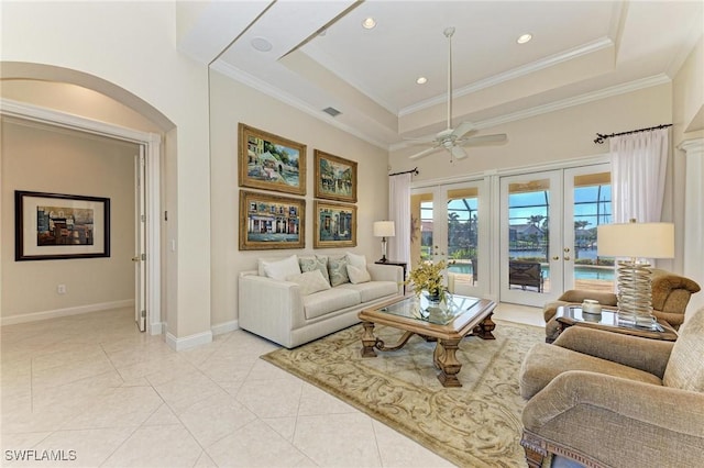 living room featuring french doors, a tray ceiling, ceiling fan, crown molding, and light tile patterned floors