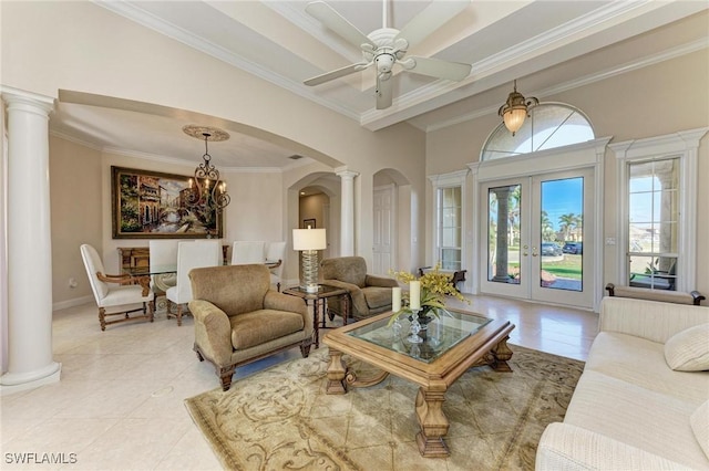 tiled living room with ceiling fan with notable chandelier, ornamental molding, french doors, and decorative columns