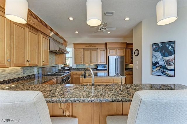 kitchen featuring dark stone countertops, kitchen peninsula, stainless steel appliances, and a breakfast bar area