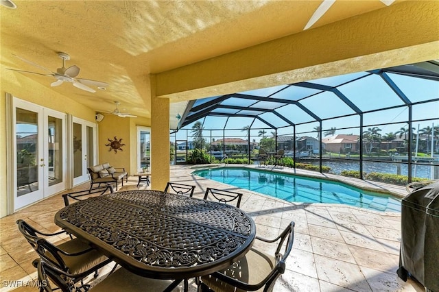 view of swimming pool featuring ceiling fan, french doors, a lanai, a water view, and a patio