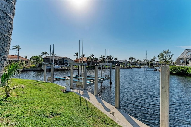 view of dock with a lawn and a water view